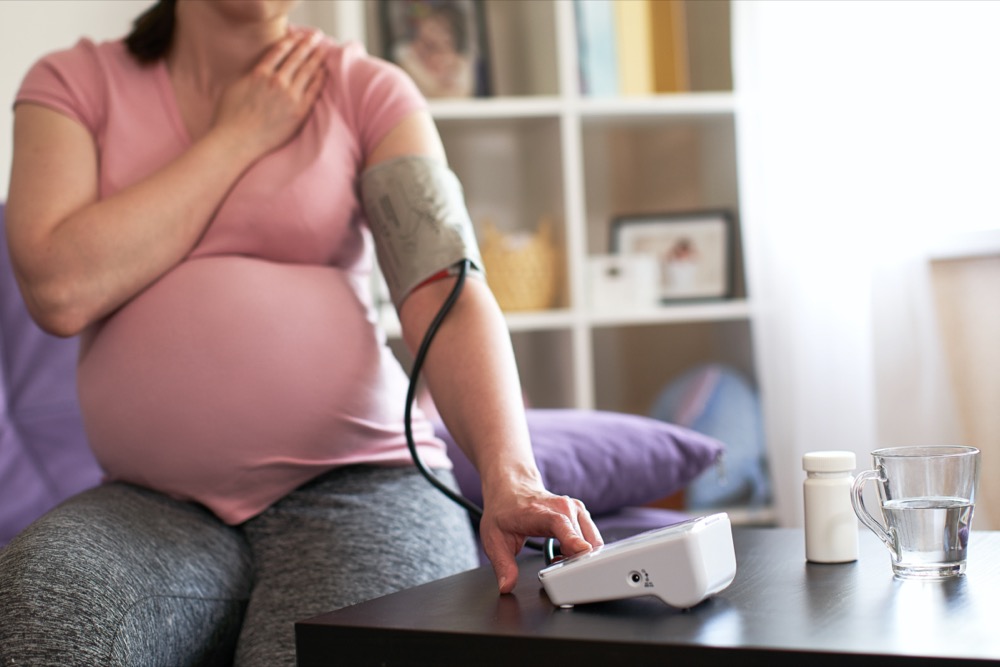Pregnant woman measuring blood pressure with an electronic pressure gauge