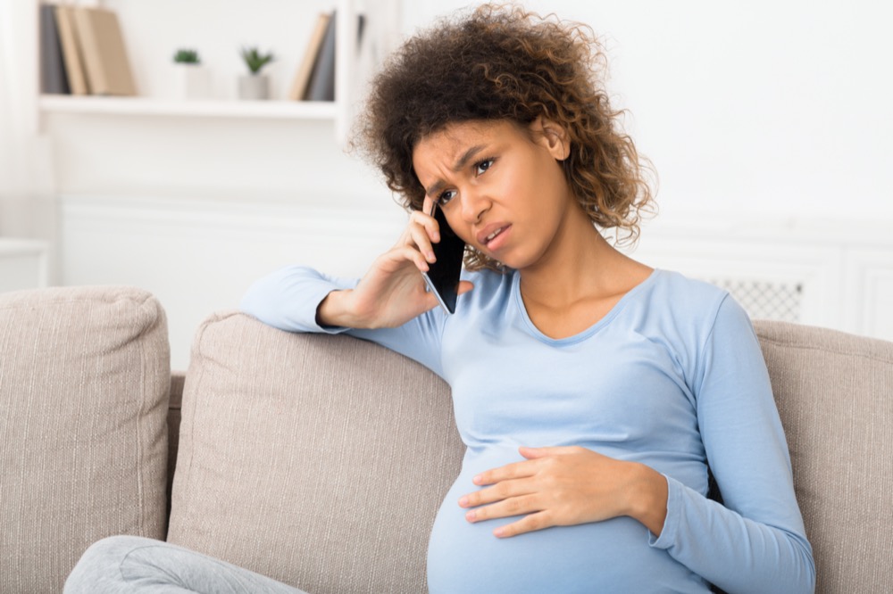 Sad pregnant woman talking on phone with her doctor